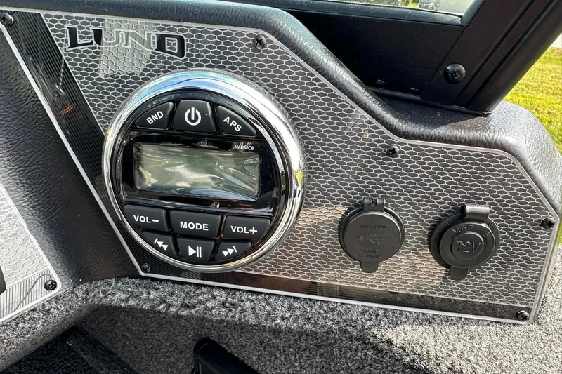 Slide: The Image of 2026 Lund 1650 Rebel XL Sport dashboard with audio controls and power outlets. - 20