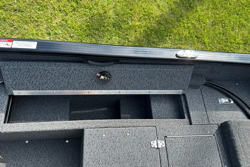 Slide: The Image of 2026 Lund 1650 Rebel XL Sport boat interior storage compartment on grassy background. - 22