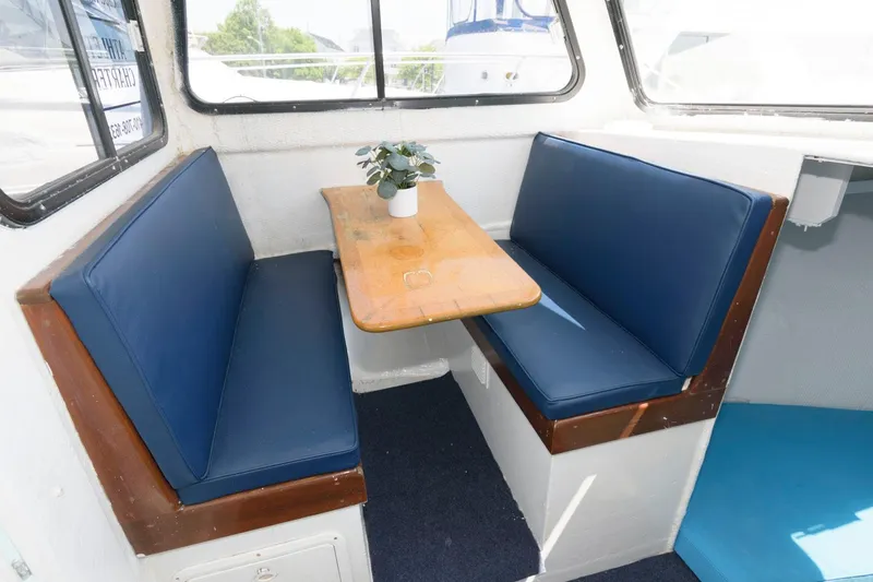 Slide: The Image of Interior of 1997 Evans 36 Deadrise boat with blue cushioned seating and wooden table. - 10