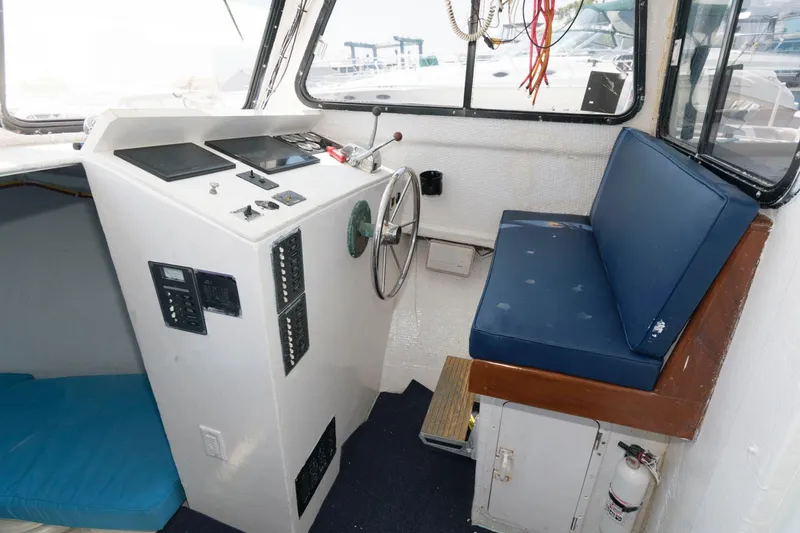 Slide: The Image of 1997 Evans 36 Deadrise boat cockpit with steering wheel, control panel, and blue cushioned seating. - 9