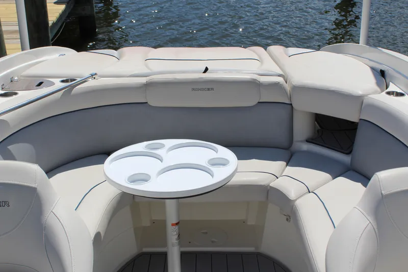 Slide: The Image of 2013 Rinker Captiva 246 BR boat interior with round table and cushioned seating. - 3