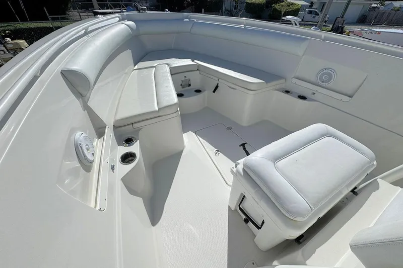 Slide: The Image of 2013 Sailfish 290 CC boat interior with white cushioned seating and cup holders. - 15