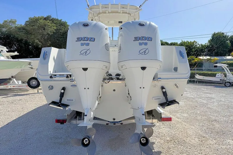 Slide: The Image of 2013 Sailfish 290 CC boat with twin 300 V6 engines, parked on gravel. - 3