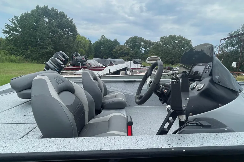 Slide: The Image of 2017 Xpress X21 boat interior with steering wheel and seats, parked outdoors. - 2