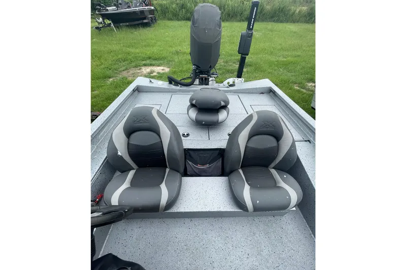 Slide: The Image of 2017 Xpress X21 boat interior with dual gray seats and motor, parked on grass. - 8