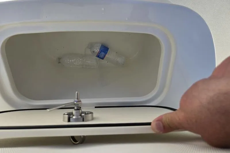 Slide: The Image of Open storage compartment on 2021 Mako 236 CC boat with plastic bottle inside. - 17