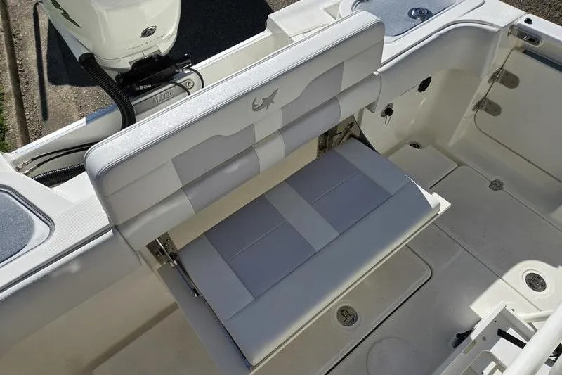 Slide: The Image of 2021 Mako 236 CC boat interior with foldable seating and motor detail. - 26