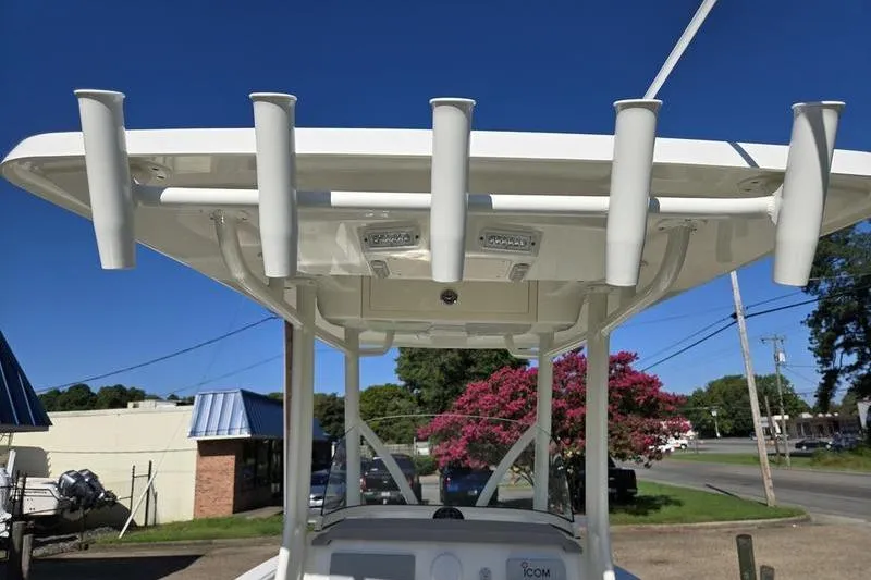 Slide: The Image of 2021 Mako 236 CC boat with rod holders and T-top, parked outdoors. - 27