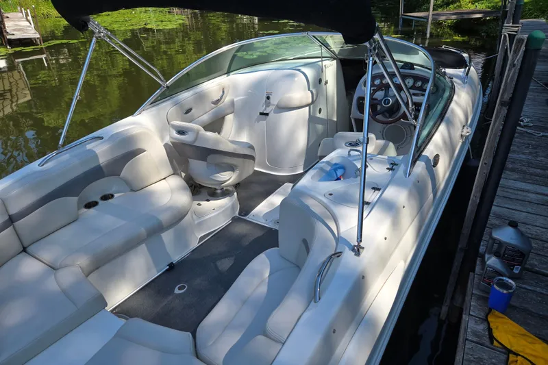 Slide: The Image of 2005 Chaparral 260 SSi boat interior with seating and steering wheel, docked by the water. - 2