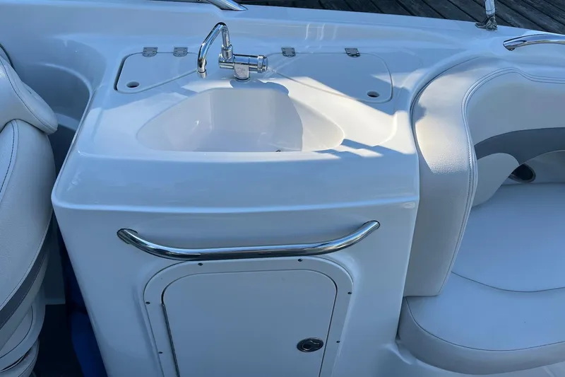 Slide: The Image of 2005 Chaparral 260 SSi boat sink and seating area, featuring sleek white design. - 21