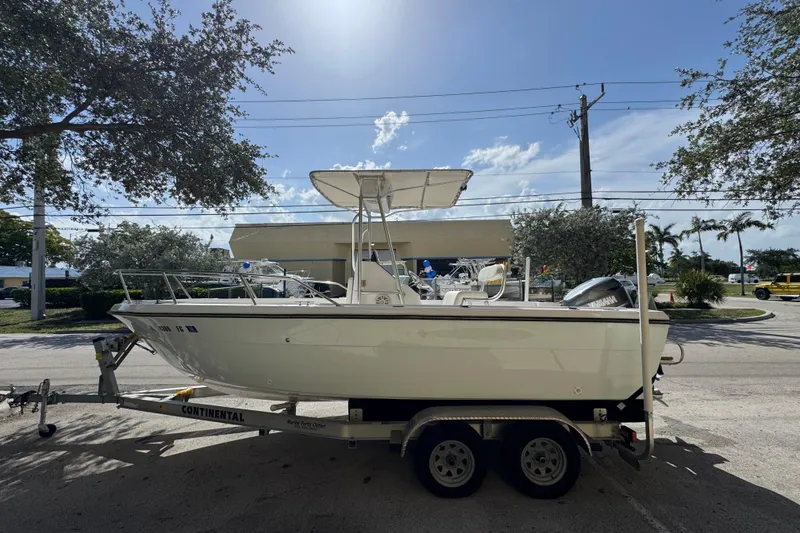 Slide: The Image of 1988 Pursuit C 200 Center Console boat on trailer, parked outdoors under clear sky. - 2