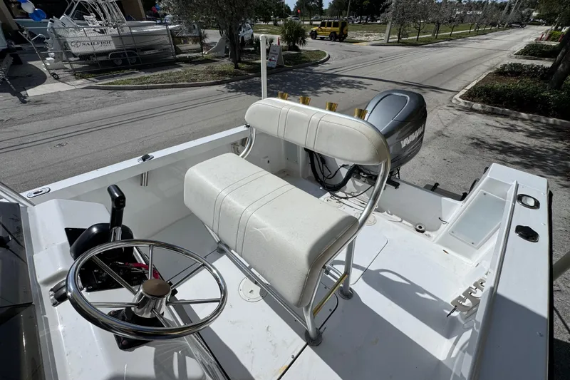 Slide: The Image of 1988 Pursuit C 200 Center Console boat with steering wheel and seating, parked outdoors. - 6