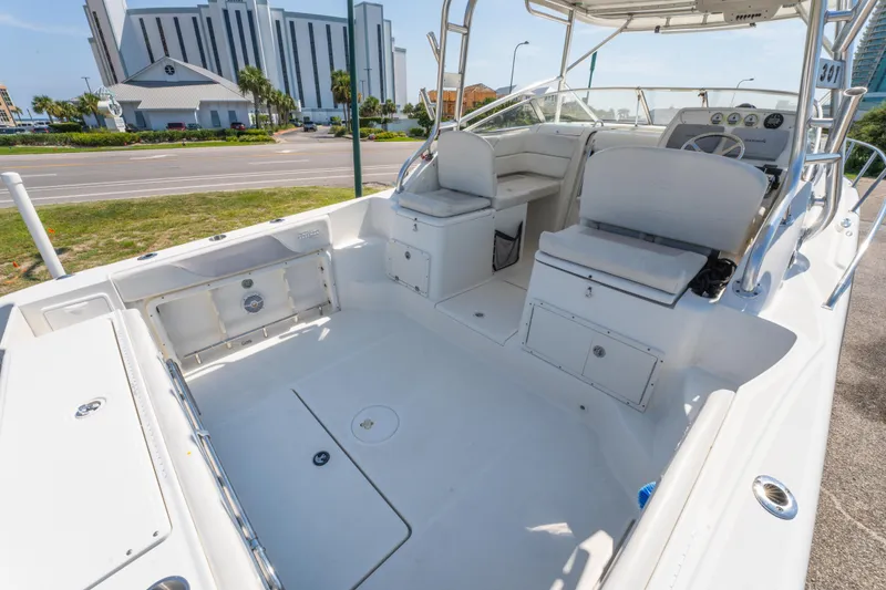 Slide: The Image of 2010 Triton 301XD boat interior with seating and steering, parked near a road. - 12