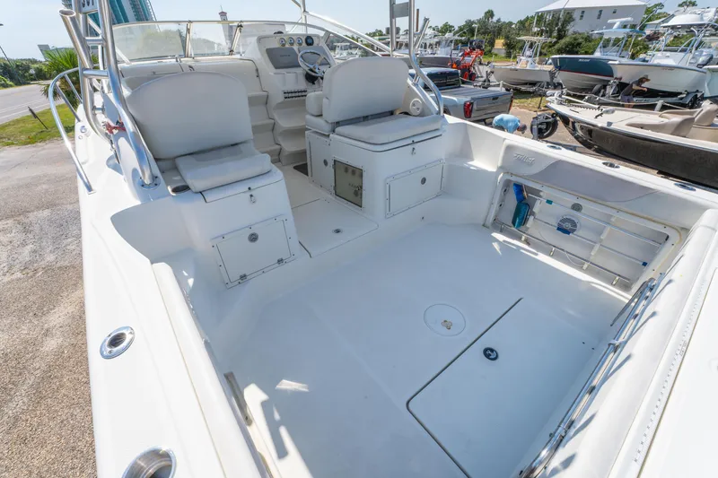 Slide: The Image of 2010 Triton 301XD boat interior with seating and storage, docked near a modern building. - 13