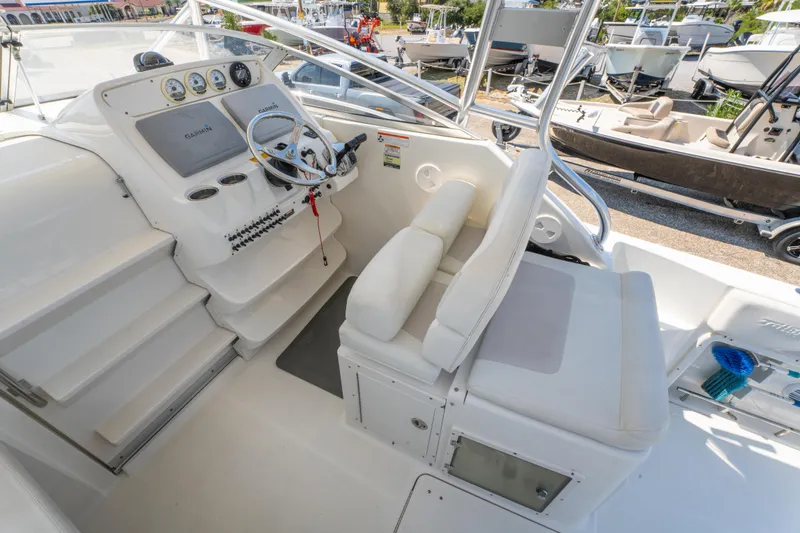 Slide: The Image of 2010 Triton 301XD boat interior with white seating and steering console. - 15