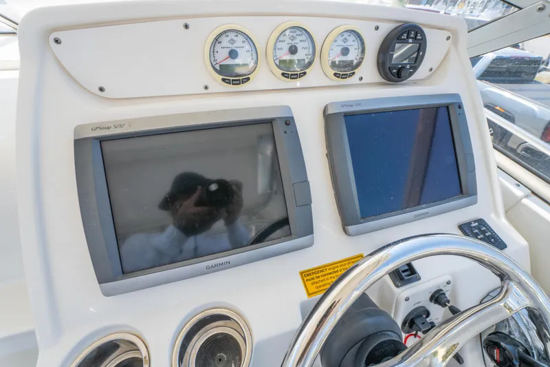 Slide: The Image of 2010 Triton 301XD boat helm with white cushioned seating and steering wheel. - 19