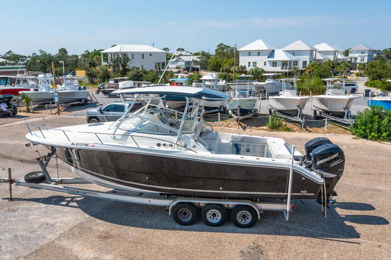 Slide: The Image of 2010 Triton 301XD boat on trailer, parked in marina with other boats and houses nearby. - 2