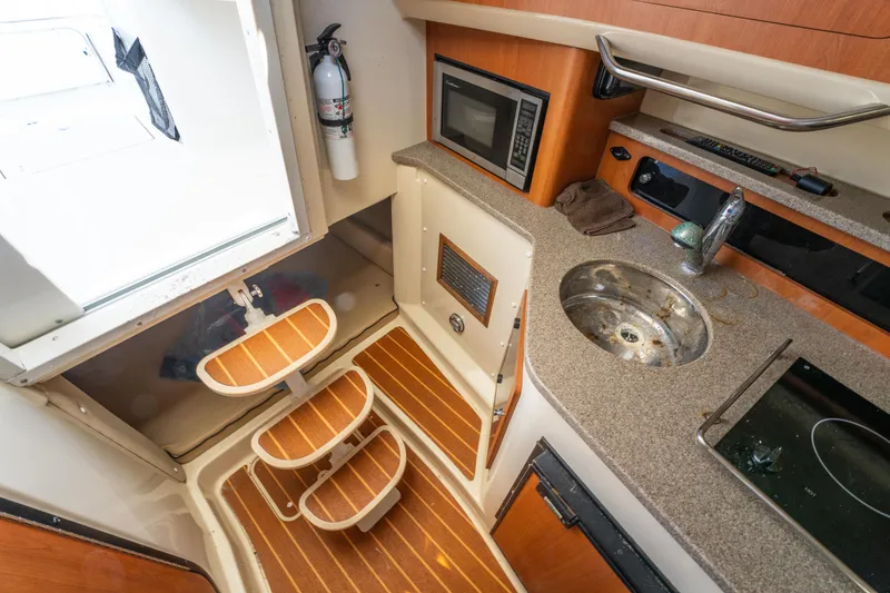 Slide: The Image of Interior of 2010 Triton 301XD boat with cushions, storage bags, and compact kitchen area. - 23