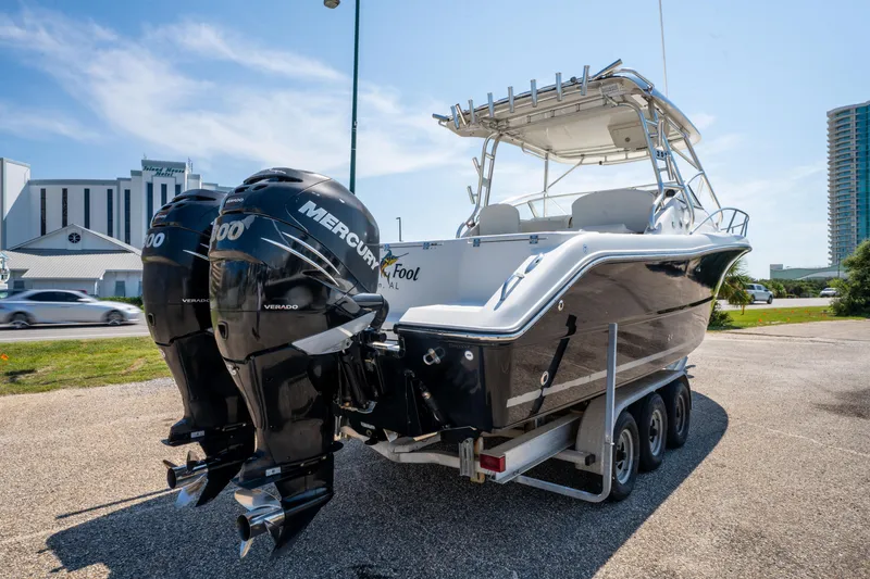 Slide: The Image of 2010 Triton 301XD boat with dual Mercury engines on a trailer, parked outdoors. - 4