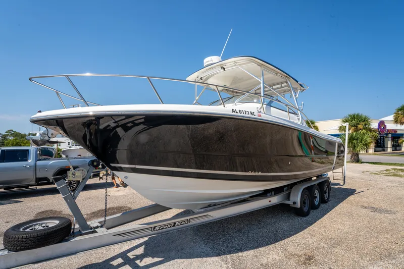 Slide: The Image of 2010 Triton 301XD boat on trailer, black hull, clear sky background. - 8