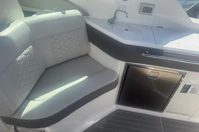Slide: The Image of 2023 Sea Ray Sundancer 320 Outboard interior with seating, sink, and mini fridge. - 21