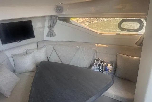 Slide: The Image of Interior of 2023 Sea Ray Sundancer 320 Outboard, featuring cozy seating and a mounted TV. - 31