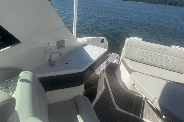 Slide: The Image of 2023 Sea Ray Sundancer 320 Outboard interior with seating and kitchenette, overlooking water. - 40