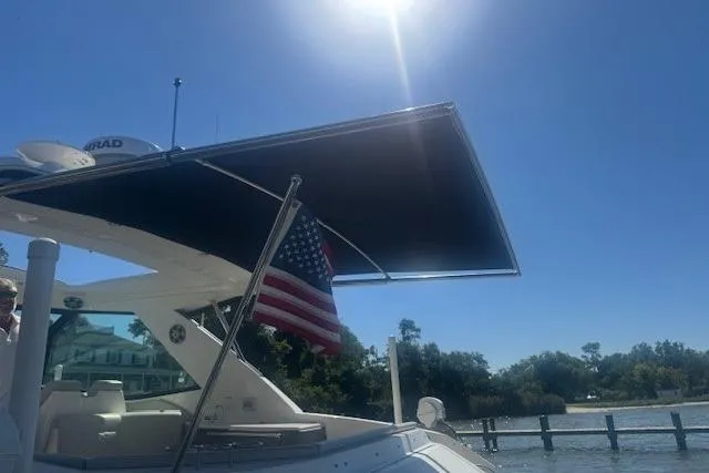 Slide: The Image of 2023 Sea Ray Sundancer 320 Outboard with American flag under sunny sky. - 47