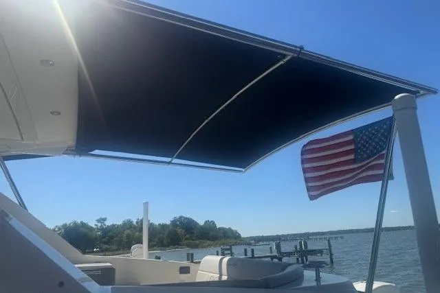Slide: The Image of 2023 Sea Ray Sundancer 320 Outboard with sunshade and American flag on a sunny day. - 5