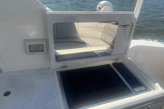Slide: The Image of 2023 Sea Ray Sundancer 320 Outboard boat grill and seating area by the water. - 9