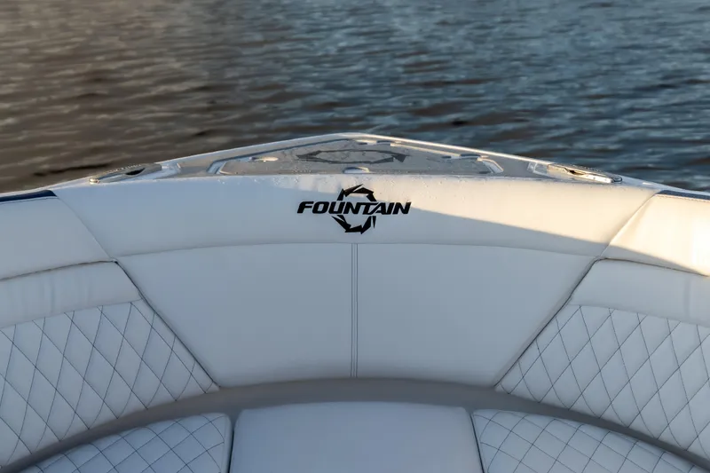 Slide: The Image of 2026 Fountain 39 DX boat interior with logo, featuring white quilted seating by the water. - 21