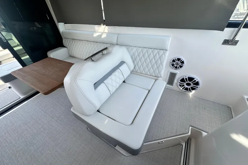Slide: The Image of 2023 Regal 36 Grande Coupe interior with white seating, wooden table, and built-in speakers. - 14