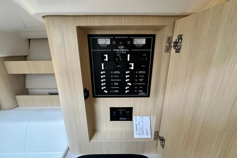 Slide: The Image of 2023 Regal 36 Grande Coupe electrical panel with switches and gauges in a wooden cabinet. - 22