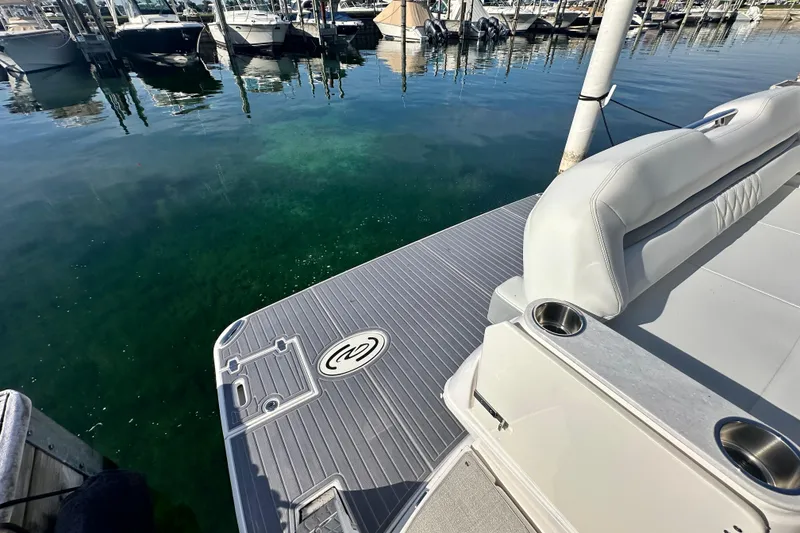 Slide: The Image of 2023 Regal 36 Grande Coupe boat deck at marina, featuring sleek seating and cup holders. - 46