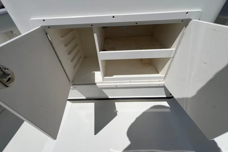 Slide: The Image of Open storage compartment on a 2003 Triton 2690 CC boat, showing shelves and doors. - 10