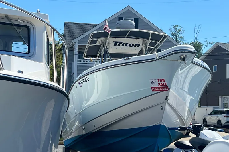 Slide: The Image of 2003 Triton 2690 CC boat for sale, docked with visible contact information. - 2