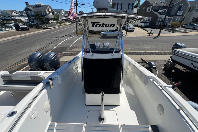 Slide: The Image of 2003 Triton 2690 CC boat with dual engines, parked near residential street. - 24