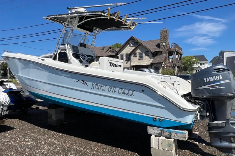 Slide: The Image of 2003 Triton 2690 CC boat with Yamaha engine, parked on blocks, residential background. - 4