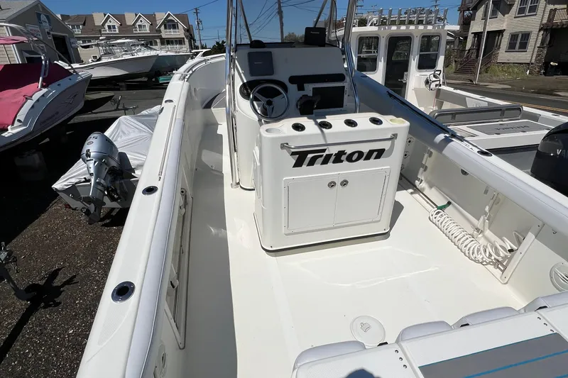 Slide: The Image of 2003 Triton 2690 CC boat interior with steering console and seating, docked outdoors. - 7