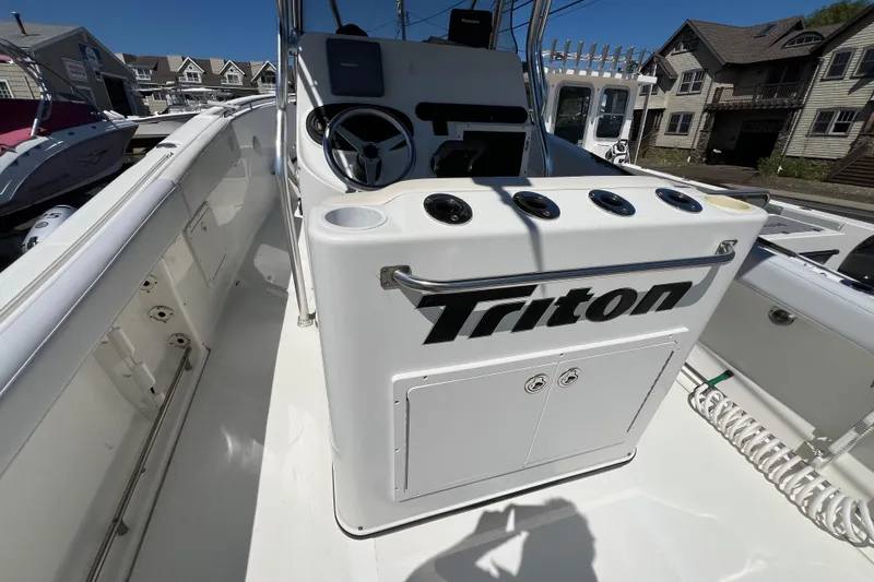 Slide: The Image of 2003 Triton 2690 CC boat interior with steering console and rod holders. - 9