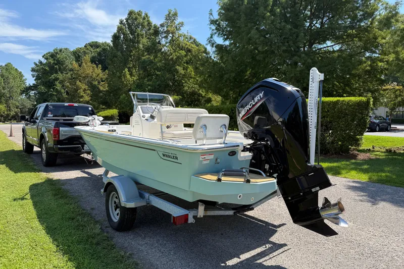 Slide: The Image of 2022 Boston Whaler 170 Montauk boat on trailer, parked near trees. - 2