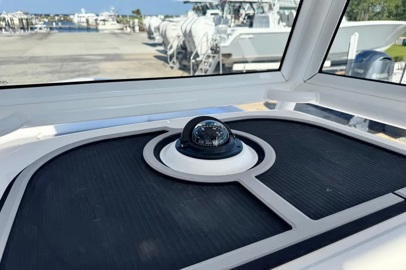 Slide: The Image of Compass on 2026 Caymas 24 HB boat dashboard, marina background. - 29