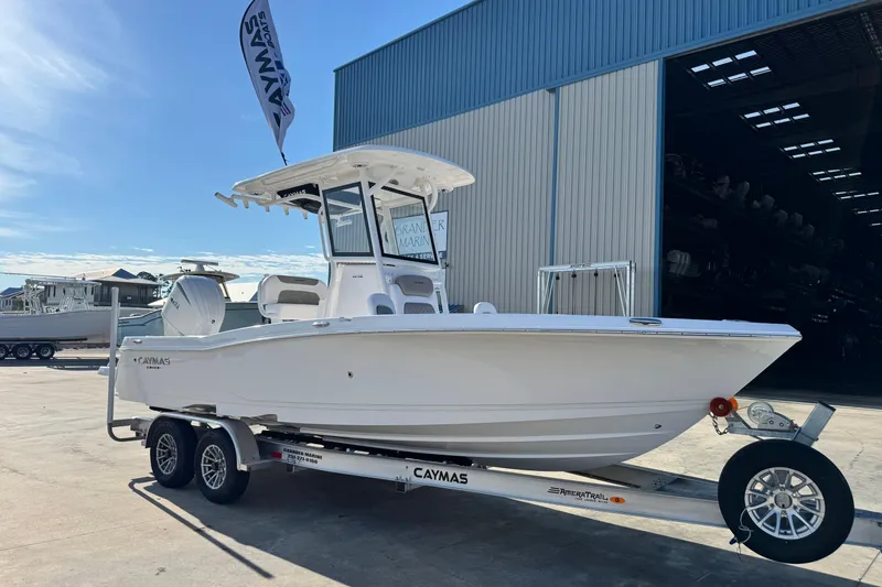 Slide: The Image of 2026 Caymas 24 HB boat on trailer outside a large warehouse. - 7