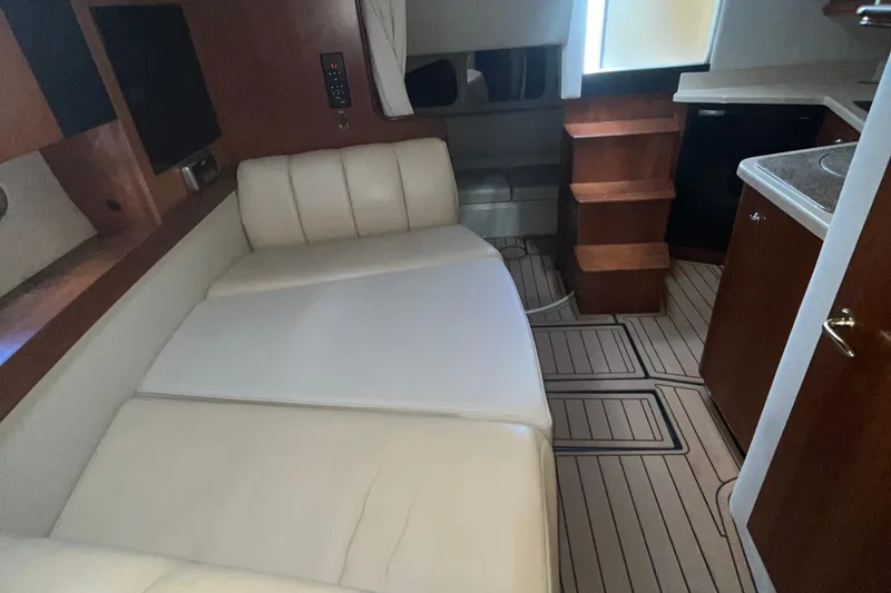 Slide: The Image of Interior of 2001 Cruisers Yachts 3470 Express with beige seating and wooden cabinetry. - 11