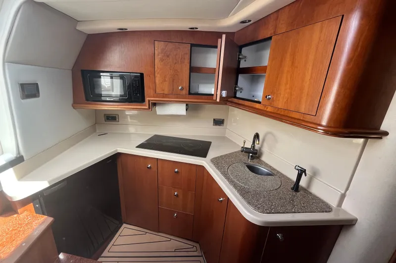Slide: The Image of 2001 Cruisers Yachts 3470 Express kitchen with wood cabinets, microwave, and sink. - 8