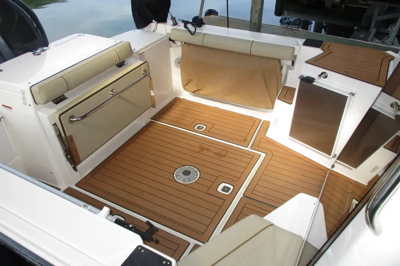 Slide: The Image of 2022 Ranger Tugs R-27 boat interior with teak flooring and cushioned seating. - 15