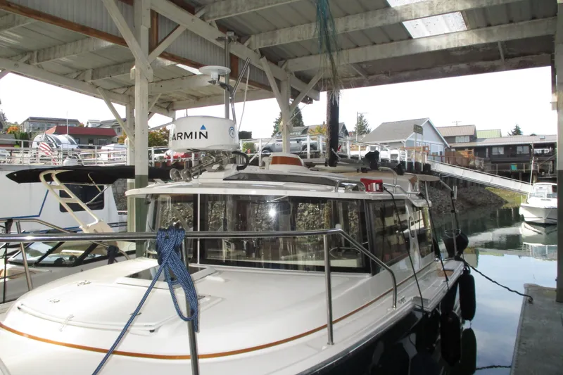 Slide: The Image of 2022 Ranger Tugs R-27 boat docked under a covered marina. - 27