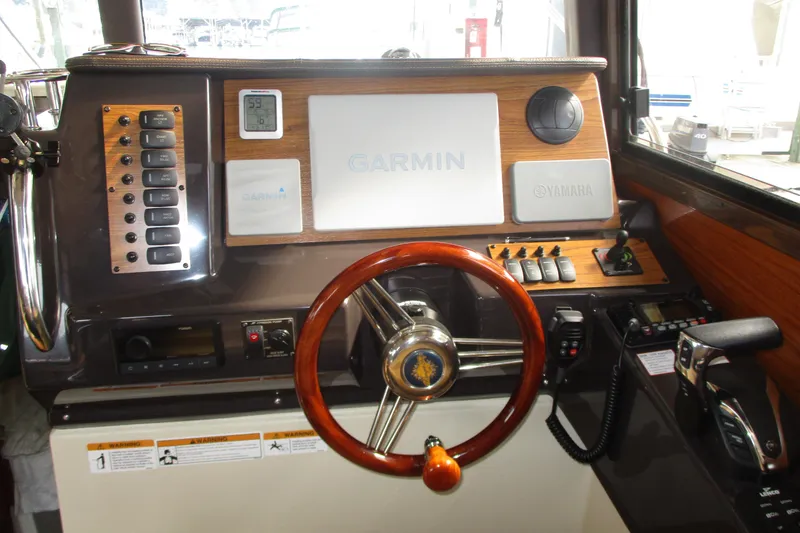 Slide: The Image of 2022 Ranger Tugs R-27 helm with Garmin navigation, Yamaha controls, and wood accents. - 42