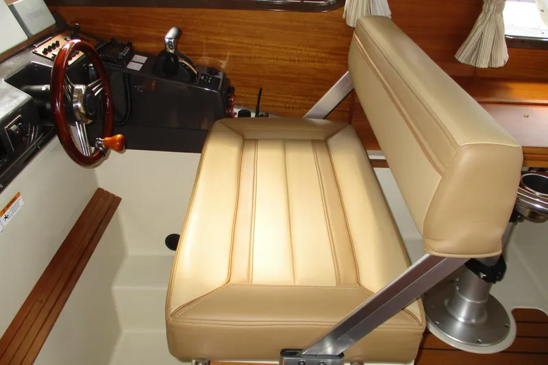 Slide: The Image of Interior helm of 2022 Ranger Tugs R-27 with beige seating and wooden accents. - 44