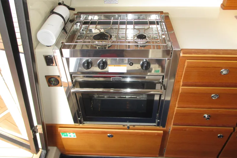Slide: The Image of 2022 Ranger Tugs R-27 galley with stainless steel stove and wooden cabinetry. - 47